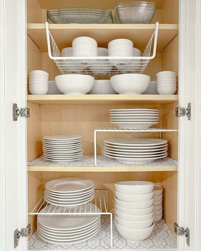 White Crockery Glows Against Patterned Shelves